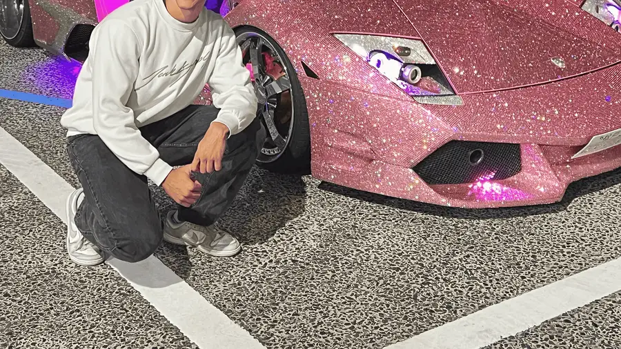 Modified Nissan Skyline GT-R parked among tuned cars at night on a daikoku pa tour in Tokyo