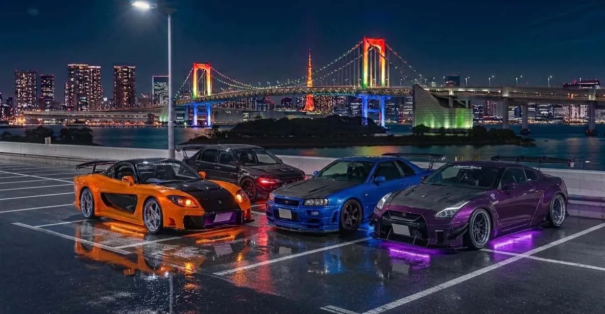Tuned sports car passing Tokyo Tower at night on a daikoku pa tour in Tokyo